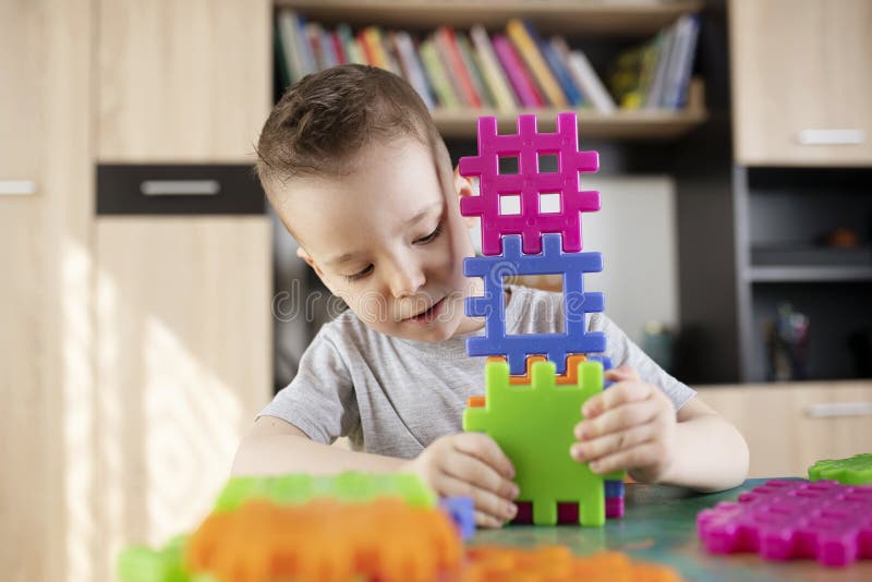 Boy playing with plastic colored building bricks stock photography