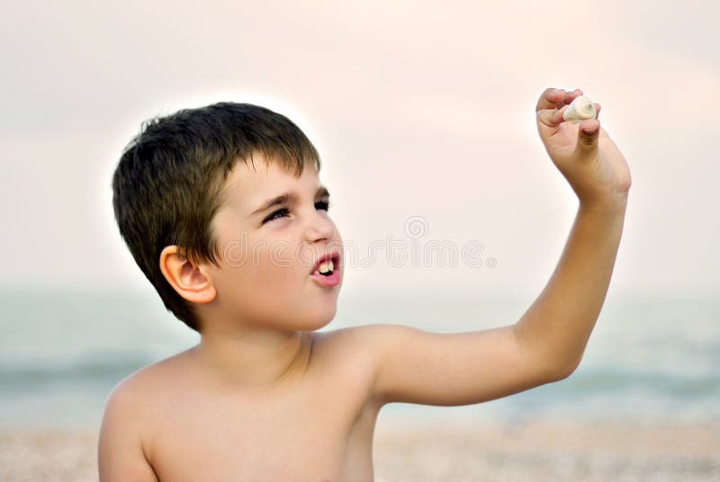 boy playing a seashell on a beach