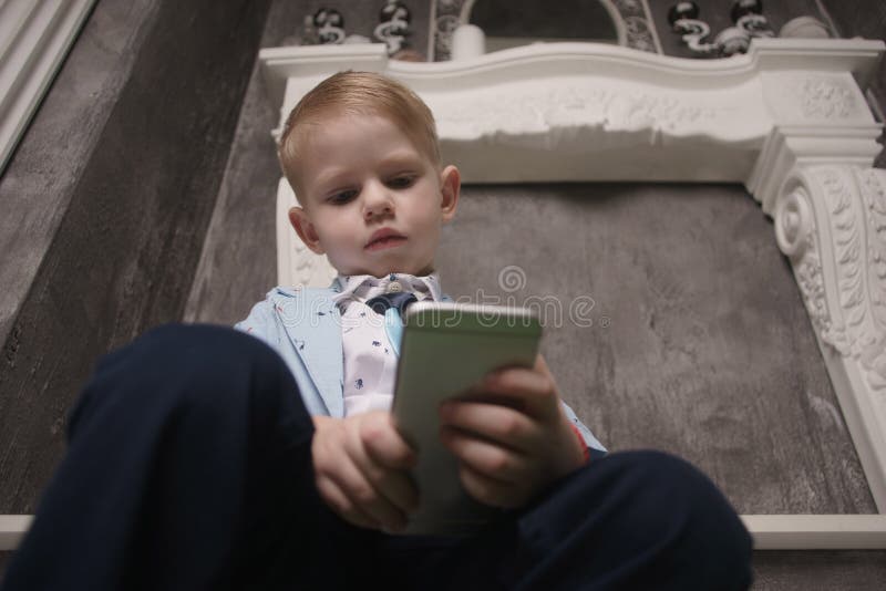 Boy playing smartphone on bed. watching smartphone. kid use phone and play game. child use mobile. addicted game and stock photos Boy playing smartphone on bed. watching smartphone. kid use phone and play game. child use mobile. addicted game and stock photos