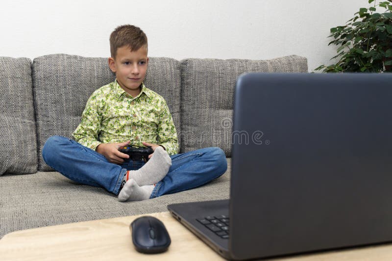 Boy playing video games with joystic sitting on sofa