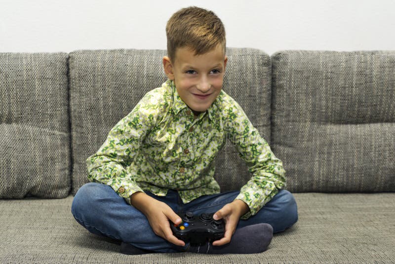 Boy playing video games with joystic sitting on sofa