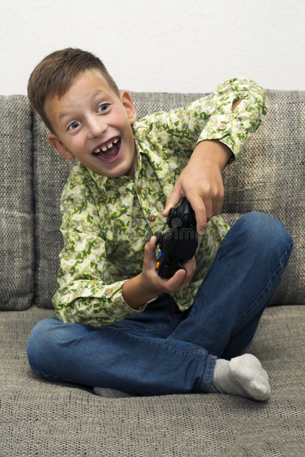 Boy playing video games with joystic sitting on sofa