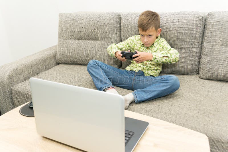 Boy playing video games with joystic sitting on sofa