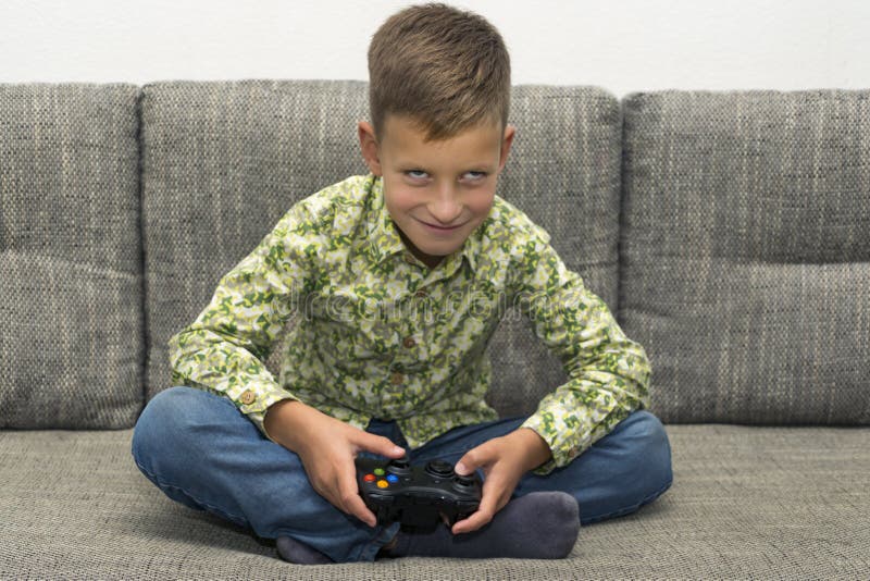 Boy playing video games with joystic sitting on sofa