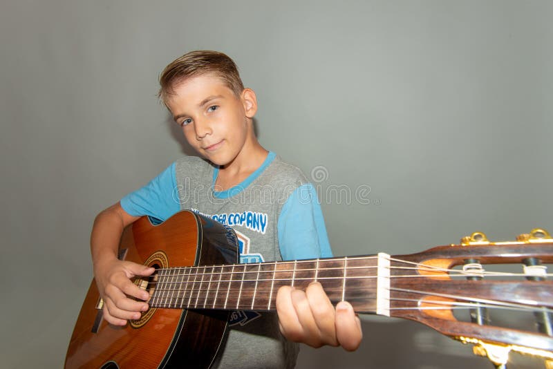 A boy plays the guitar, wide-angle photo in the studio of a musical child stock photo A boy plays the guitar, wide-angle photo in the studio of a musical child stock photo