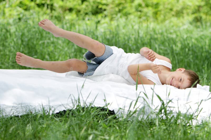 Boy relaxing on white bed on natural background