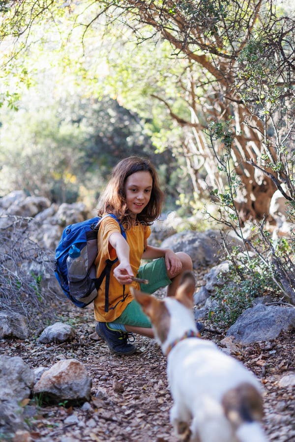 Boy Rests While Trekking And Plays With A Dog A Boy With A Backpack Plays On A Mountain Path Boy Rests While Trekking And Plays With A Dog A Boy With A Backpack Plays On A Mountain Path