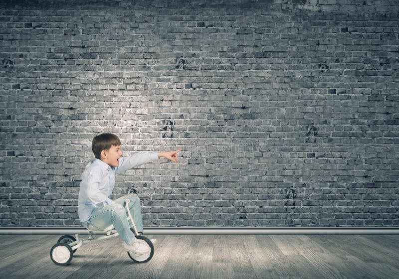 Little joyful cute boy riding tricycle in empty room. Little joyful cute boy riding tricycle in empty room