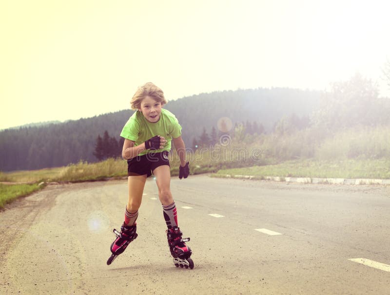 Boy riding on rollers on the road near the field