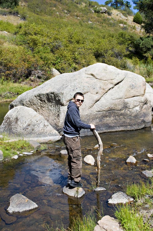 Boy in the river by a boulder