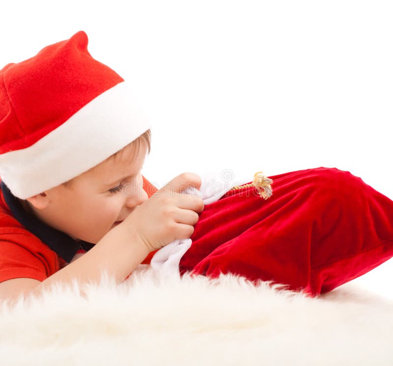 Boy in Santa s hat open christmas bag with gifts