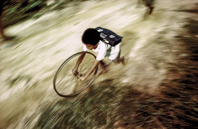 Boy in school uniform runs back home playing with a wheel of a b