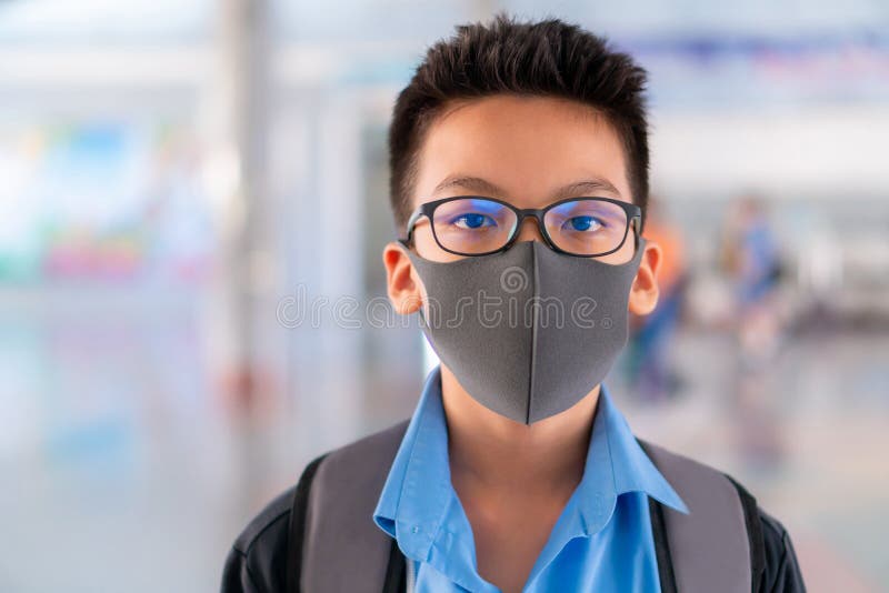 Boy in school uniform wearing a surgical mask with blurred background, Virus protection concept royalty free stock photography Boy in school uniform wearing a surgical mask with blurred background, Virus protection concept royalty free stock photography