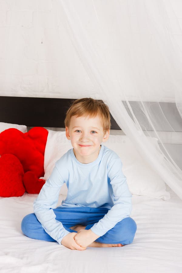 Boy sits on a bed in a comfortable situation