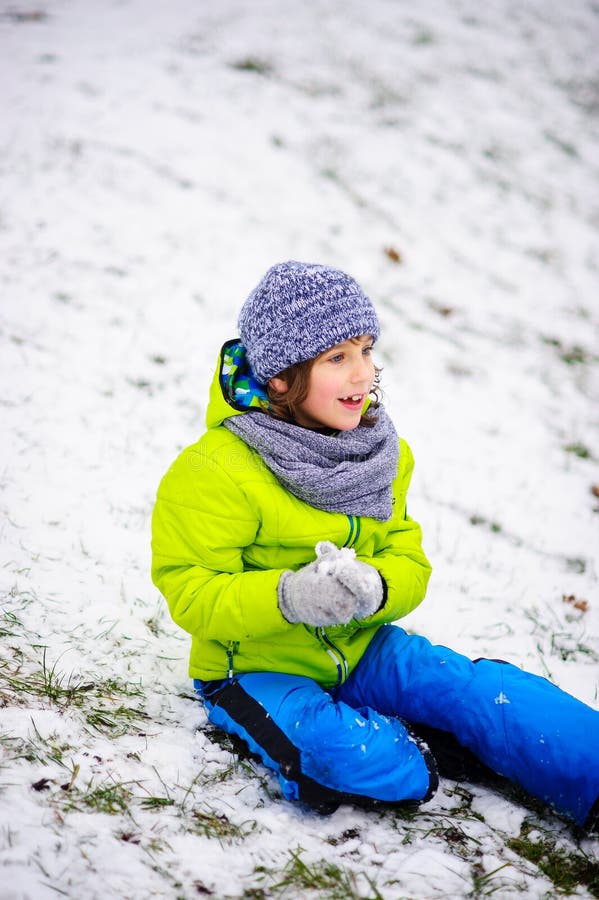 Boy sits on the ground which is slightly covered with the first snow. stock images