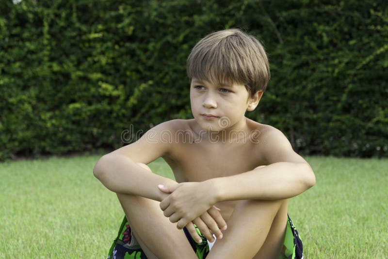 The boy sits on a lawn