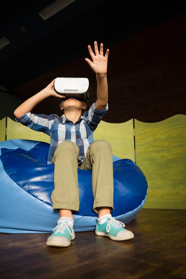 Boy Sitting on Bean Bag and Using Virtual Reality Headset Stock Photo