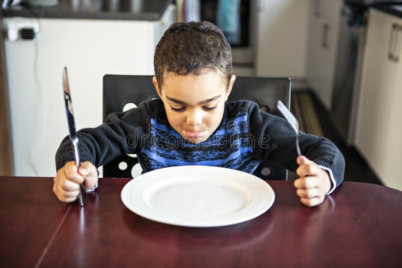 Boy Sitting at the Kitchen Table with Empty Plate Stock Photo Image