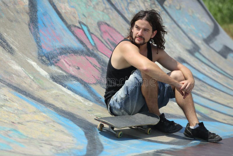 Boy sitting with a skateboard on a half pipe stock image Boy sitting with a skateboard on a half pipe stock image
