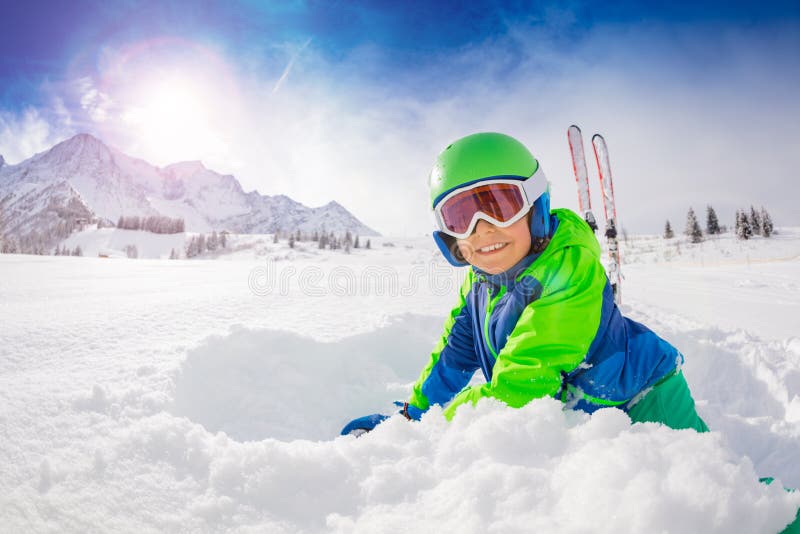 Boy with ski play in fresh deep snow smiling