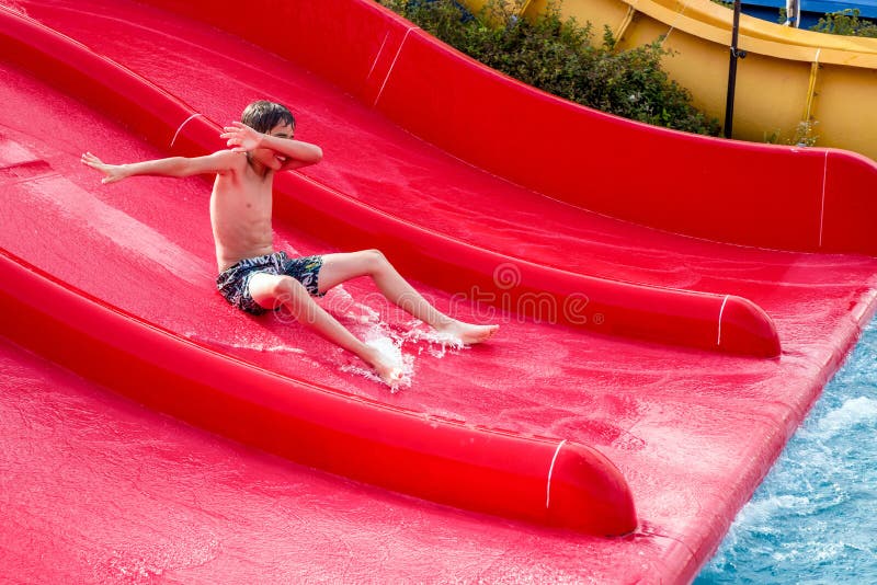 Boy sliding on a water slide stock photos