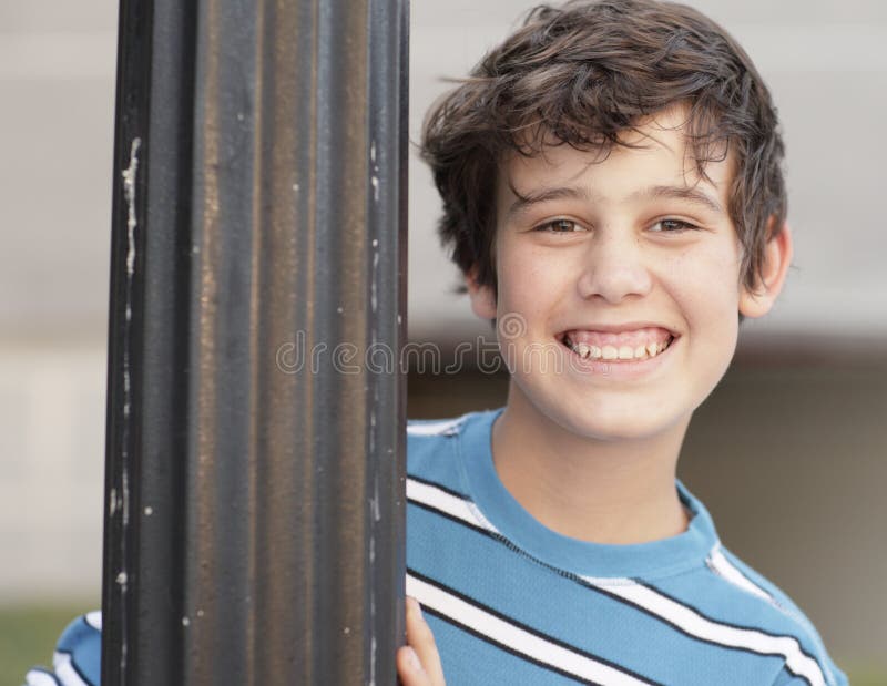 Boy smiling from behind a pole