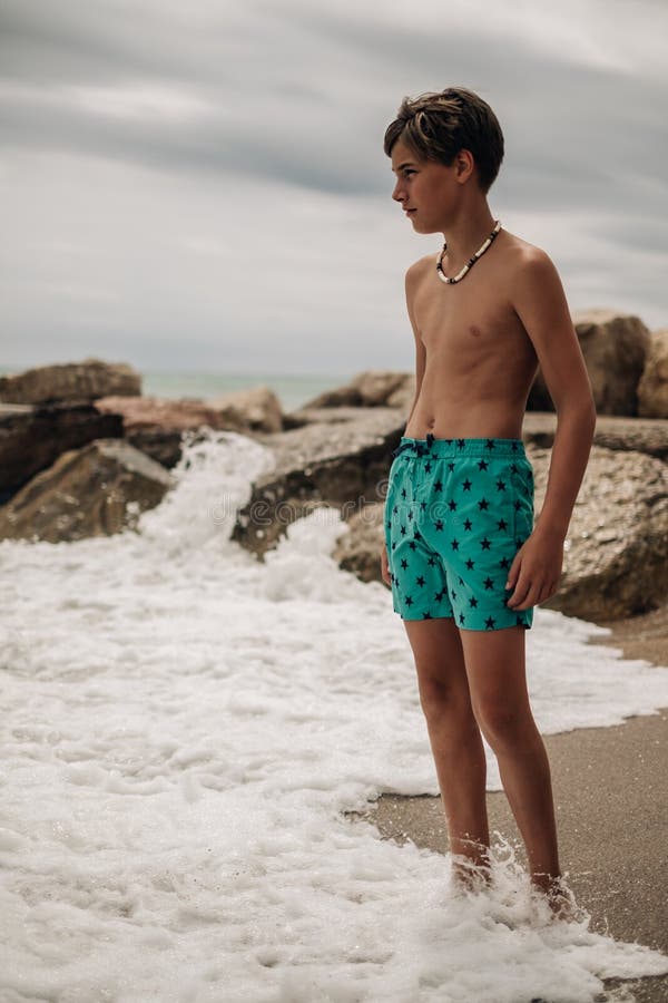 Boy Sitting on the Rock while Waves Hitting His Leg Stock Im