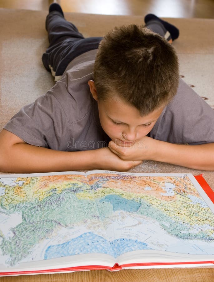 Un giovane adolescente disteso sul tappeto, studiando una mappa.