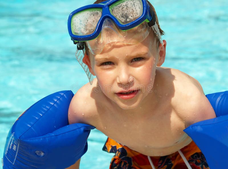 Mladý chlapec, plávanie s modrým rameno floaties a masku.