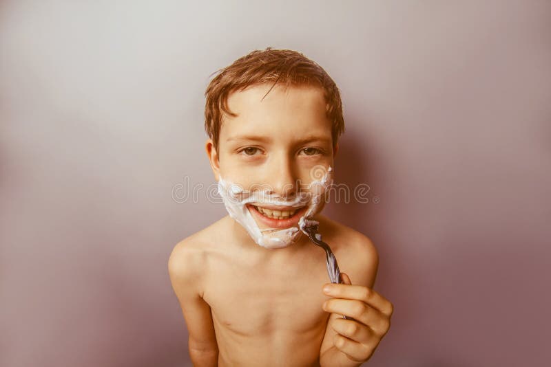 Boy teenager European appearance decade shaves face on a gray background retro
