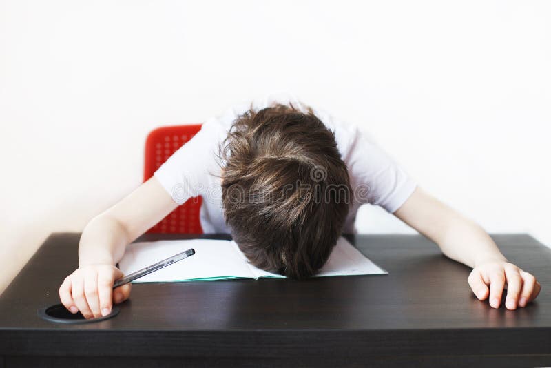 The boy is tired of doing homework. child sits and does homework royalty free stock photography