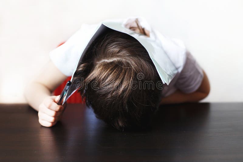 The boy is tired of doing homework. child sits and does homework stock photos