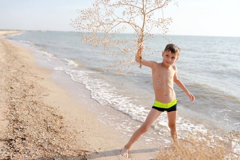 Boy with tumbleweed plant on beach of Azov sea