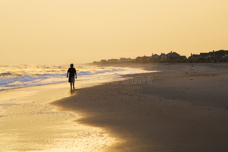 Boy walking on beach at sunset