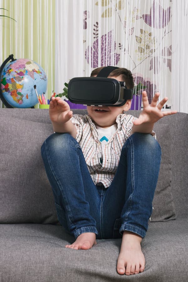 Boy is Watching Video with Virtual Reality Glasses, Indoors. Digital