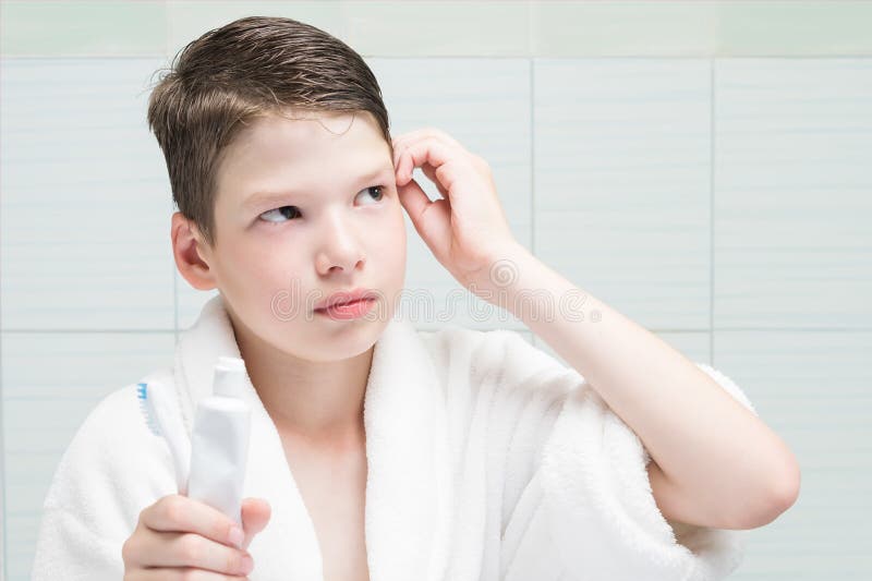 A boy in a white coat came to the bathroom in the morning to brush his teeth and wash royalty free stock photos A boy in a white coat came to the bathroom in the morning to brush his teeth and wash royalty free stock photos