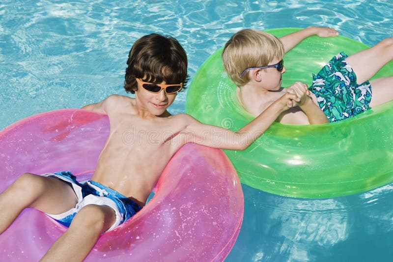 Boys On Float Tubes In Swimming Pool stock photo