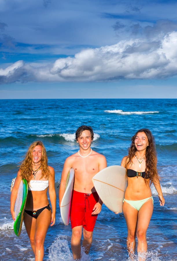 Boys and girls teen surfers coming out from the beach stock image.