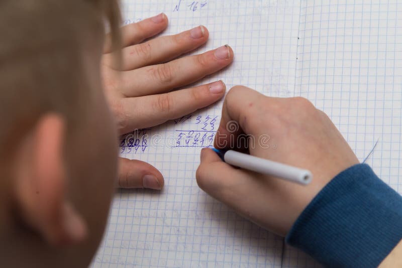 The boys hands with a ballpoint pen solve a close-up math example. royalty free stock image