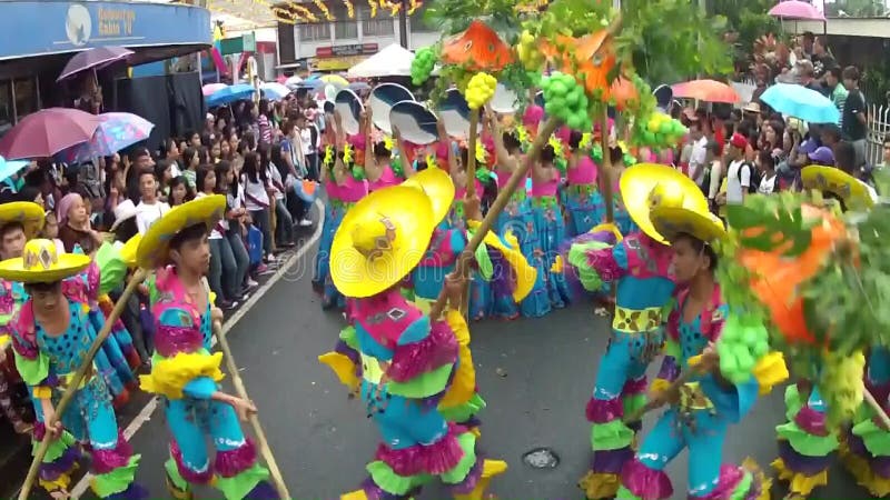 Boys in ornate coconut costume dance along the street, a festival to honor a patron saint