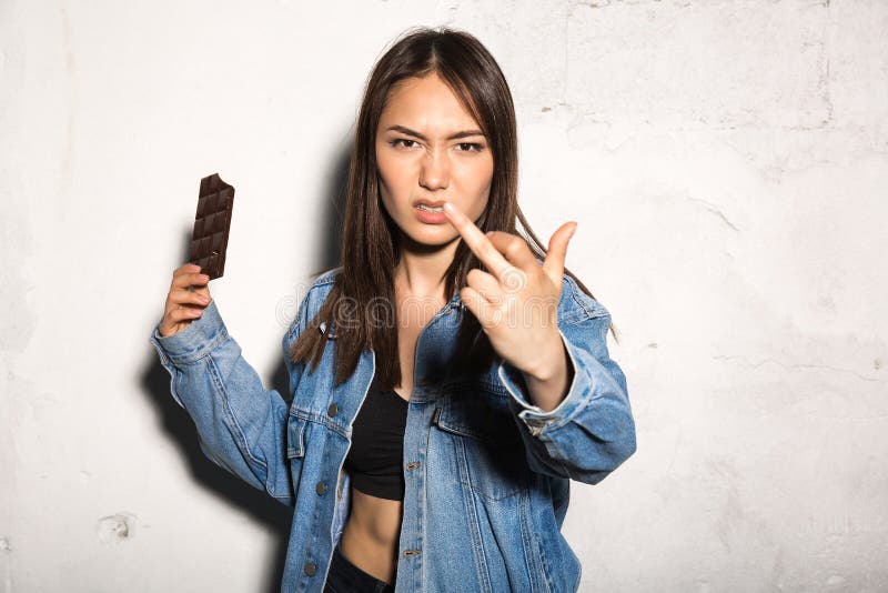Boze hipstervrouw die chocolade eten die middelvinger tonen stock foto Boze hipstervrouw die chocolade eten die middelvinger tonen stock foto