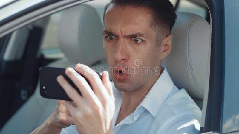 Boze man die smartphone gebruikt terwijl hij in een auto zit. zakenman is kwaad op de boodschap dat hij smartphone leest.
