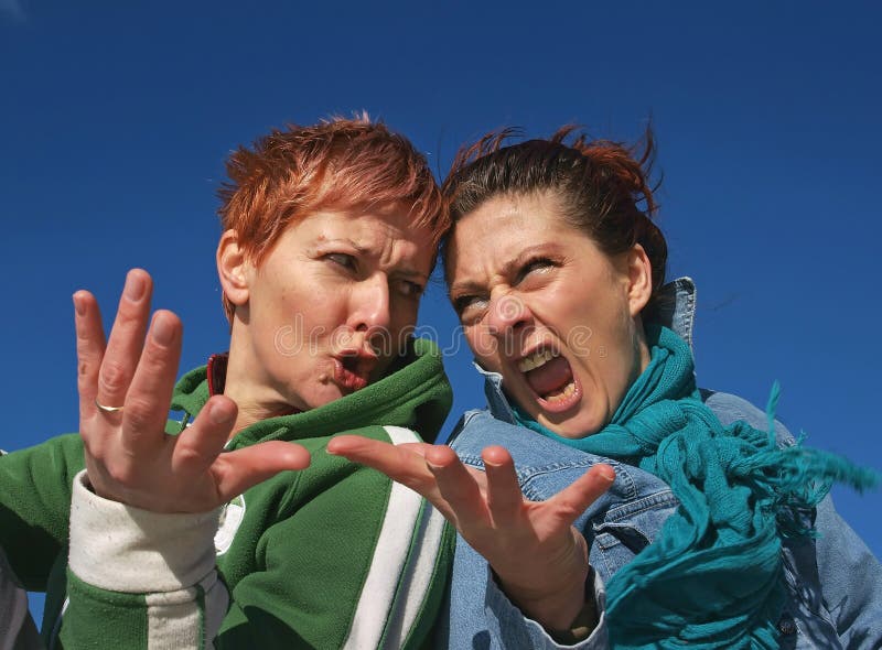 Two woman of scowling and angry faces, (pissed off) they are fight and argue fiercely gesturing hands. Horizontal color photo. Two woman of scowling and angry faces, (pissed off) they are fight and argue fiercely gesturing hands. Horizontal color photo.