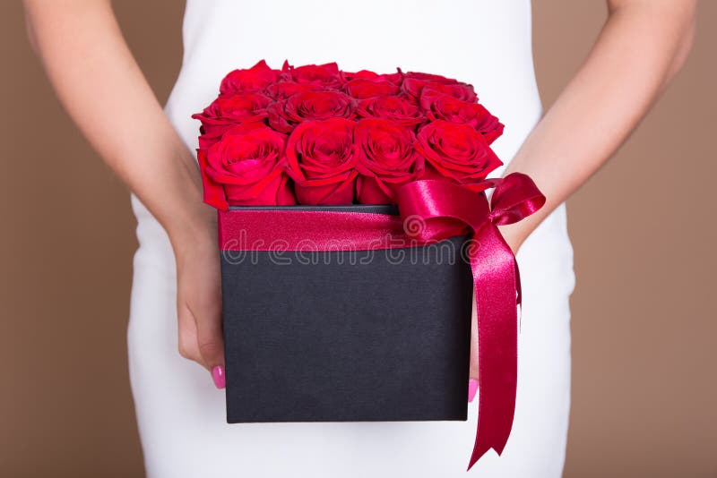 Boîte avec les roses rouges dans des mains femelles image stock Boîte avec les roses rouges dans des mains femelles image stock