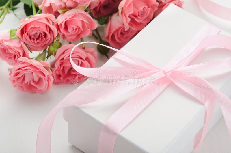 Boîte-cadeau blanc avec un ruban rose et un bouquet des roses sur un fond blanc Un cadeau pour la Saint-Valentin, anniversaire photos stock Boîte-cadeau blanc avec un ruban rose et un bouquet des roses sur un fond blanc Un cadeau pour la Saint-Valentin, anniversaire photos stock