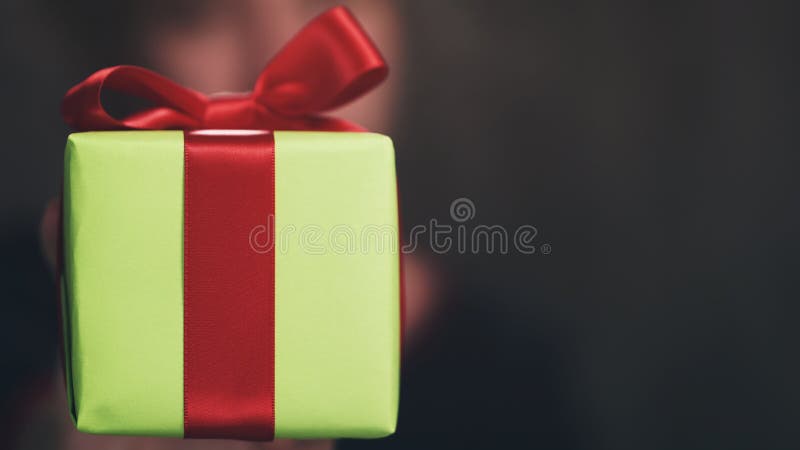 Boîte-cadeau de l'adolescence femelle de Livre vert d'exposition de main avec l'arc rouge photographie stock Boîte-cadeau de l'adolescence femelle de Livre vert d'exposition de main avec l'arc rouge photographie stock