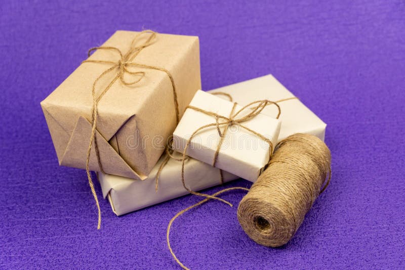Boîtes-cadeaux emballées dans du papier jaunâtre ancien et réenroulées avec une corde d'un sac à dos de corde image libre de droits