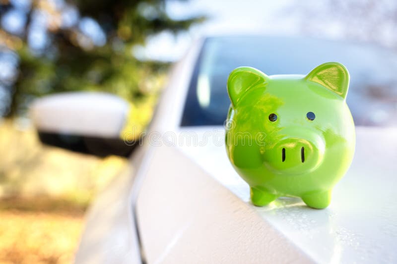 Boîte à monnaie de la banque de pige verte sur le toit de la voiture nouvelle assurance achat de véhicule ou le coût de la conduit images libres de droits
