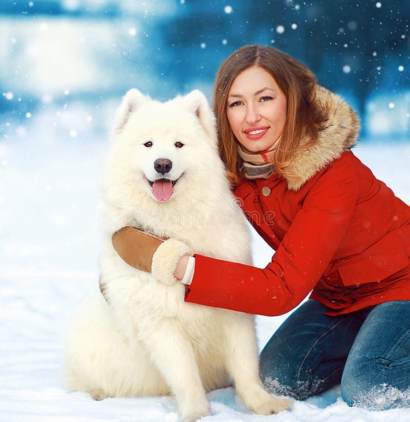 Bożenarodzeniowego portreta szczęśliwa uśmiechnięta kobieta z białym Samoyed psem na śniegu w zima dniu zdjęcie royalty free Bożenarodzeniowego portreta szczęśliwa uśmiechnięta kobieta z białym Samoyed psem na śniegu w zima dniu zdjęcie royalty free