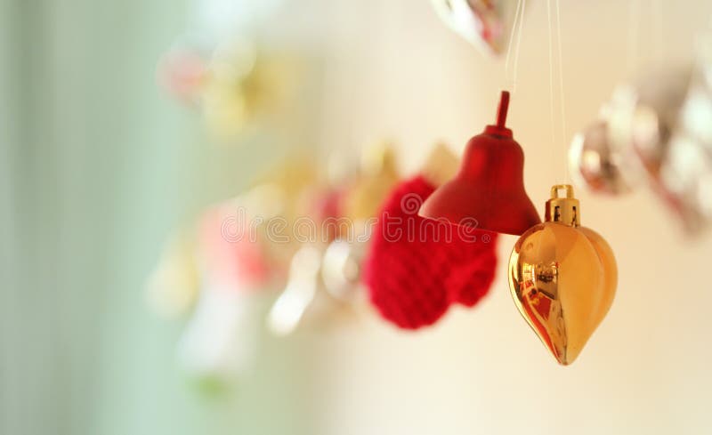 Christmas decoration ornaments. Bell, heart and gloves shape toys hanging on wall with blur gold background. Giving a warm and family loving feeling. For Christmas, new year and seasons greeting. Christmas decoration ornaments. Bell, heart and gloves shape toys hanging on wall with blur gold background. Giving a warm and family loving feeling. For Christmas, new year and seasons greeting.